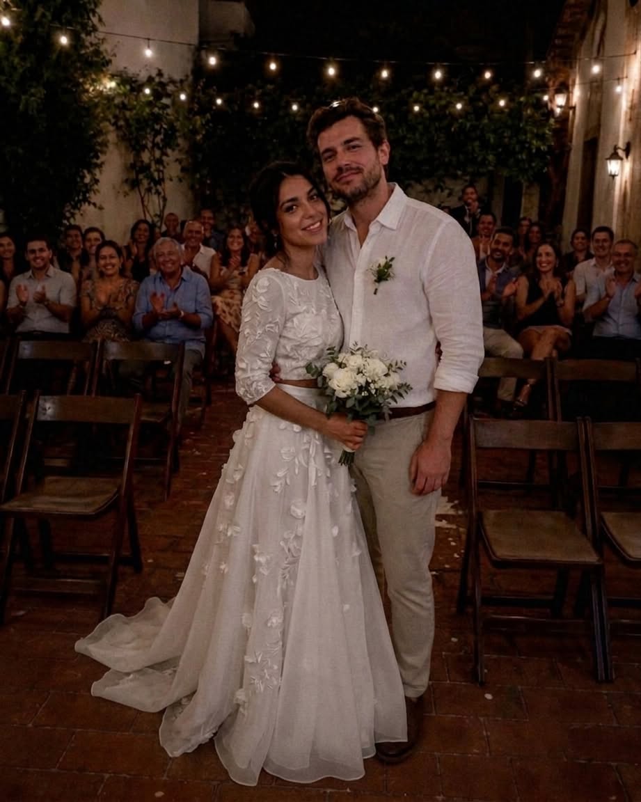 My husband’s family boycotted our wedding because he was ‘marrying down’ — two years later, my MIL came back with one unexpected request.  The day my husband and I got married, every seat reserved for his family stayed empty.  A week before the wedding, his mother had told him,  “If you marry her, don’t expect any of us to be there.”  Her reason was simple.  My mother had been a waitress for over thirty years, and my father owned a small auto repair shop.  Meanwhile, my husband’s family owned several successful businesses and had always expected him to marry someone from “their world.”  Apparently…  I wasn’t.  He married me anyway.  We had a beautiful wedding despite the empty seats, and after that, he completely cut ties with his family.  Over the next two years, we bought our first house, talked about having children, and I eventually stopped wondering whether his family would ever accept me.  Then, one rainy Saturday morning, someone knocked on our door.  When I opened it, my mother-in-law was standing there.  For several seconds, neither of us spoke.  Her eyes drifted into the house until they landed on the framed wedding photo hanging in our hallway.  She stared at it for a long moment.  “You still keep it there,” she said quietly.  I wasn’t sure how to respond.  Finally, she sighed.  “I almost turned around three times before knocking.”  For a second, I honestly thought she’d come to apologize.  I stepped aside to let her in.  “Before I show you why I came,” she said, “I need you to promise me something.”  “What?”  “Promise you won’t tell my son I came here until you’ve seen everything.”  I stared at her for a moment before finally nodding.  Only then did she pull a thick envelope from her purse and place it on the table.  “I need you to look at these.”  Inside were several photographs.  The first showed my husband sitting across from a woman at a café.  Another showed them leaving an office building together.  In a third, they were walking through a park while she appeared to be wiping tears from her face, and my husband had a hand on her shoulder.  None of the pictures proved anything.  But together…  they made my stomach twist.  I looked up at my mother-in-law.  “Who is she?”  She slowly shook her head.  “I don’t know.”  I frowned.  “Then why are you showing me this?”  She looked down at her hands.  “For two years, I kept waiting for your marriage to fall apart.”  A sad smile crossed her face.  “I was convinced my son had made the biggest mistake of his life.”  She paused before continuing.  “But it never happened.”  Another silence filled the room.  Finally, she said,  “A few weeks ago… these ended up in my hands.”  She gently pushed the envelope back toward me.  “I don’t know who that woman is.”  “I thought you needed to know the truth.”  After she left, I sat at the kitchen table for nearly an hour.  I kept trying to come up with innocent explanations.  Then I remembered a business trip he’d unexpectedly extended by a day. A few weeks later, he’d stepped outside to answer a phone call, saying he needed better reception.  Around the same time, I’d found a receipt from a restaurant he’d never mentioned. None of those moments had seemed important back then.  Looking at the photographs now…  I wasn’t so sure anymore.  When my husband came home that evening, I was still sitting at the kitchen table with the envelope in front of me.  He smiled as he walked through the door.  Then his eyes landed on the photographs.  The smile disappeared immediately.  I picked up one of them.  My hands were shaking.  “Who is she?”  He stared at the picture for several long seconds.  Then he looked at me.  “… Mom showed you these?”  “Yes.”  He didn’t answer right away.  Instead, he asked quietly,  “Did she make you promise not to tell me she’d been here?”  I felt my stomach drop.  “Yes.”  He closed his eyes.  “Then she already knows exactly what she’s done.” Read the REST of this story in 1st comment⬇️